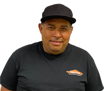 Man in black SERVPRO shirt with white hat against white backdrop