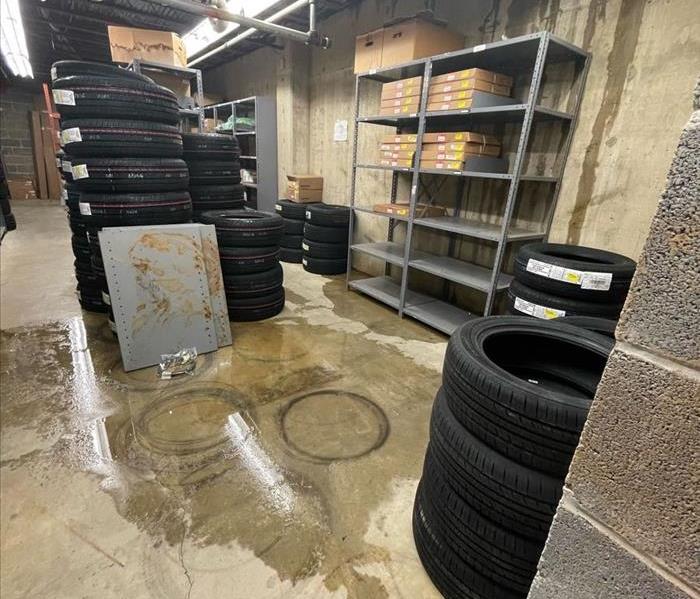 Commercial warehouse storing tires with leaking water pooling on the floor and dripping down the walls.